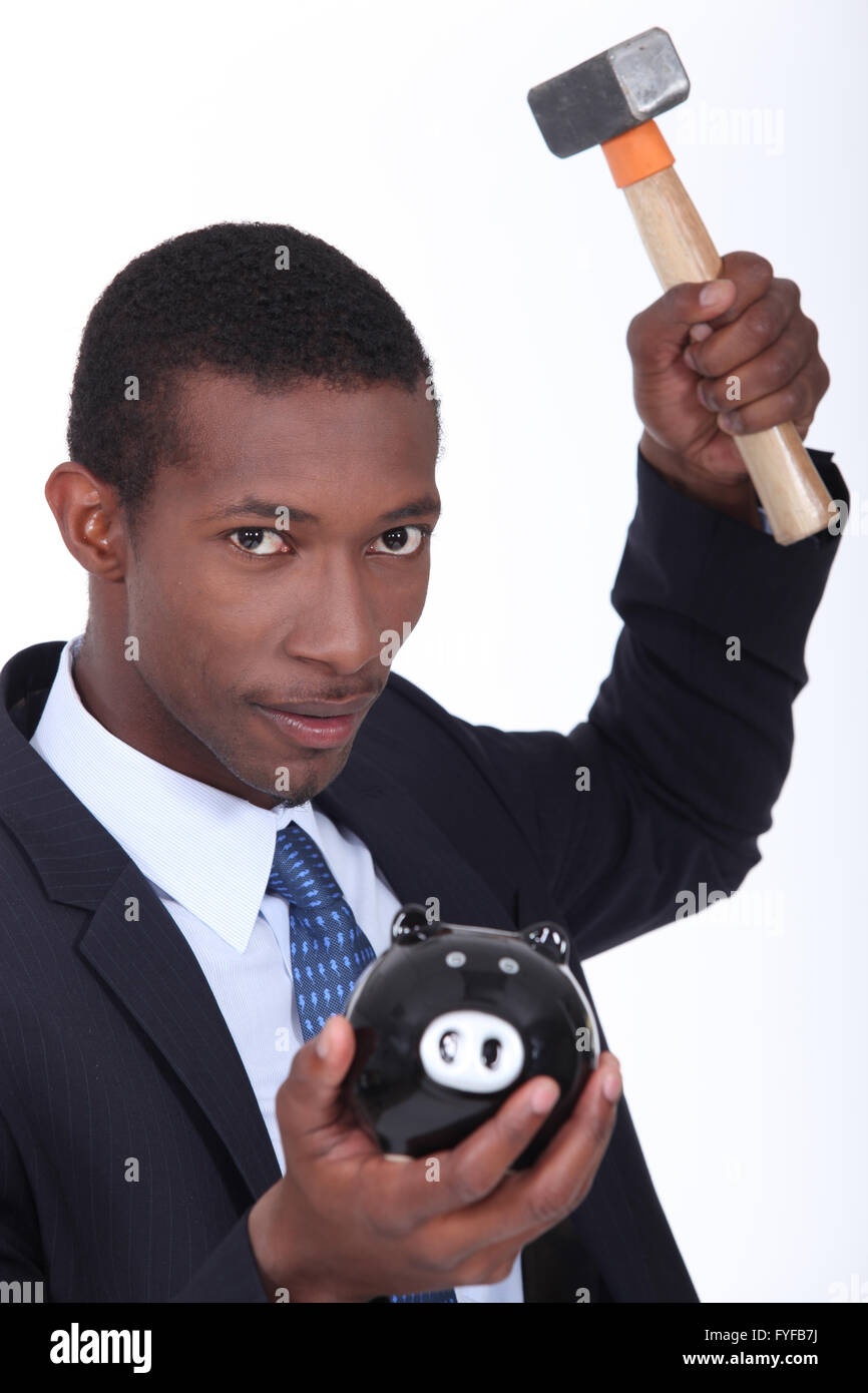L'uomo circa per rompere un salvadanaio con un martello Foto Stock
