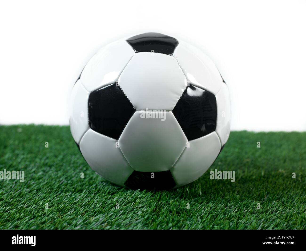 Bianco e nero palloni da calcio isolati su erba artificiale Foto Stock