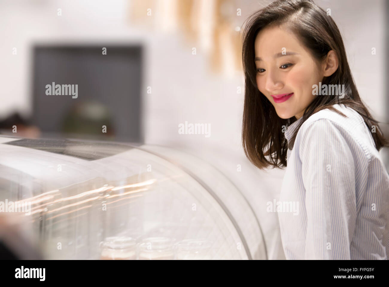 Negoziante nella parte anteriore del display cabinet nel panificio Foto Stock