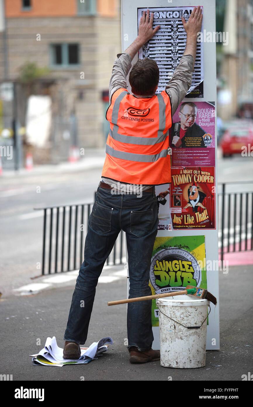 Un lavoratore di Festival di Edimburgo appeso un poster in Edinburgh Street come un Festival di Edimburgo promozione. Pic da pak@ Mera Foto Stock