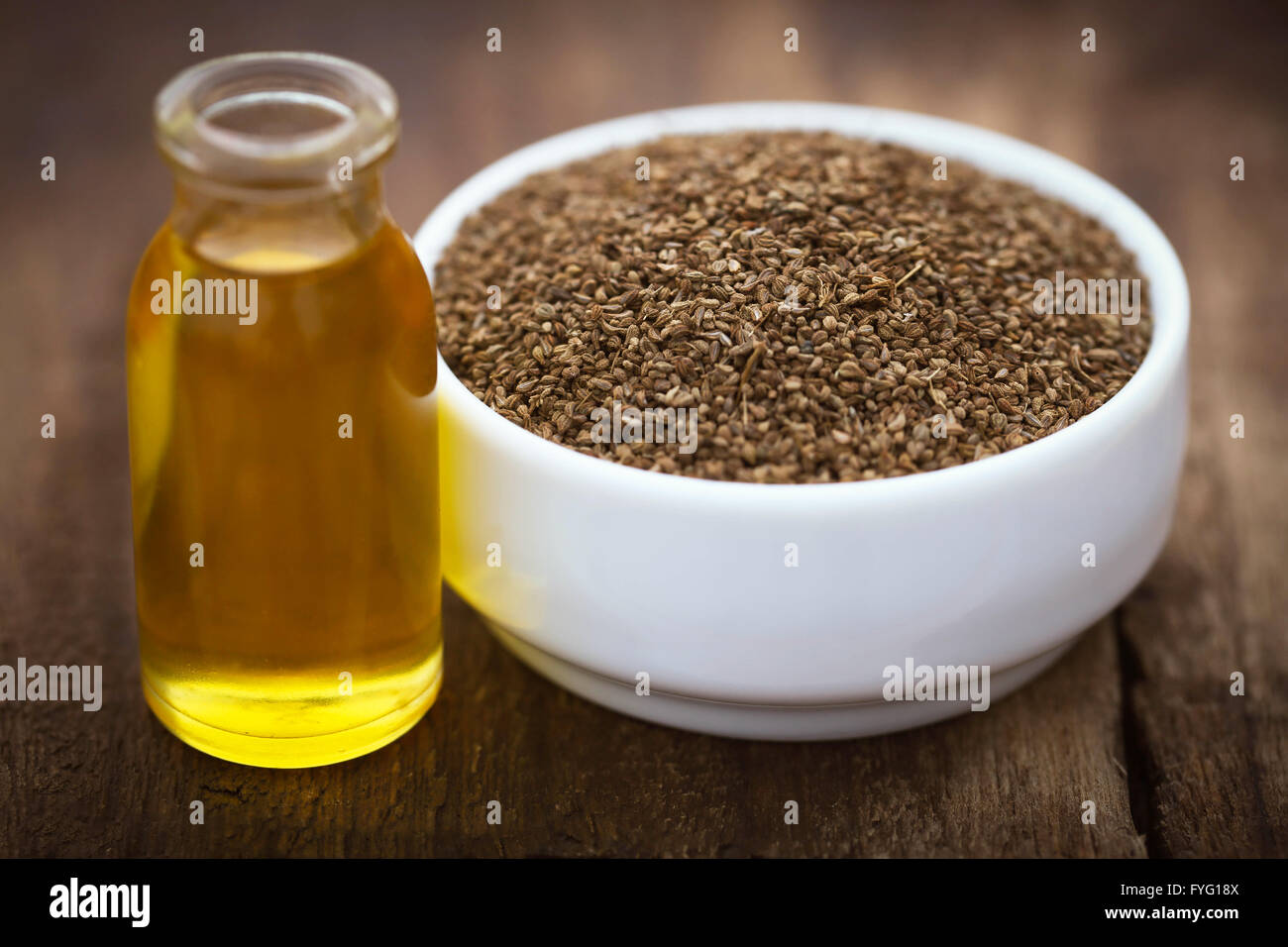 Semi di Ajwain in un recipiente con olio essenziale su una superficie di legno Foto Stock