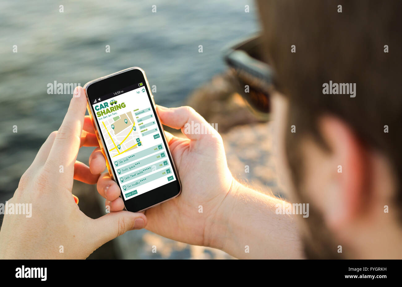 L uomo sulla costa con car sharing app sul suo smartphone . Tutti i grafici dello schermo sono costituiti. Foto Stock