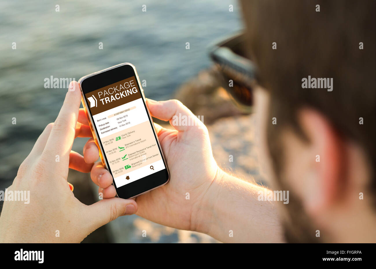 L uomo sulla costa package tracking su un web sul suo smartphone. Tutti i grafici dello schermo sono costituiti. Foto Stock