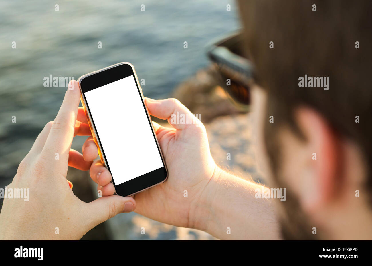 L uomo sulla costa, utilizzando il suo smartphone con schermo vuoto Foto Stock
