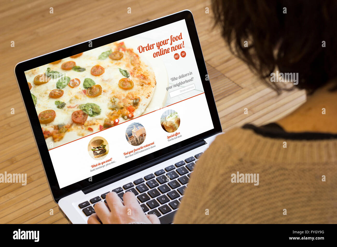Ordinazione di prodotti alimentari online il concetto: la donna con un computer portatile che mostra il fast food sito web sullo schermo. Grafici dello schermo sono costituiti. Foto Stock
