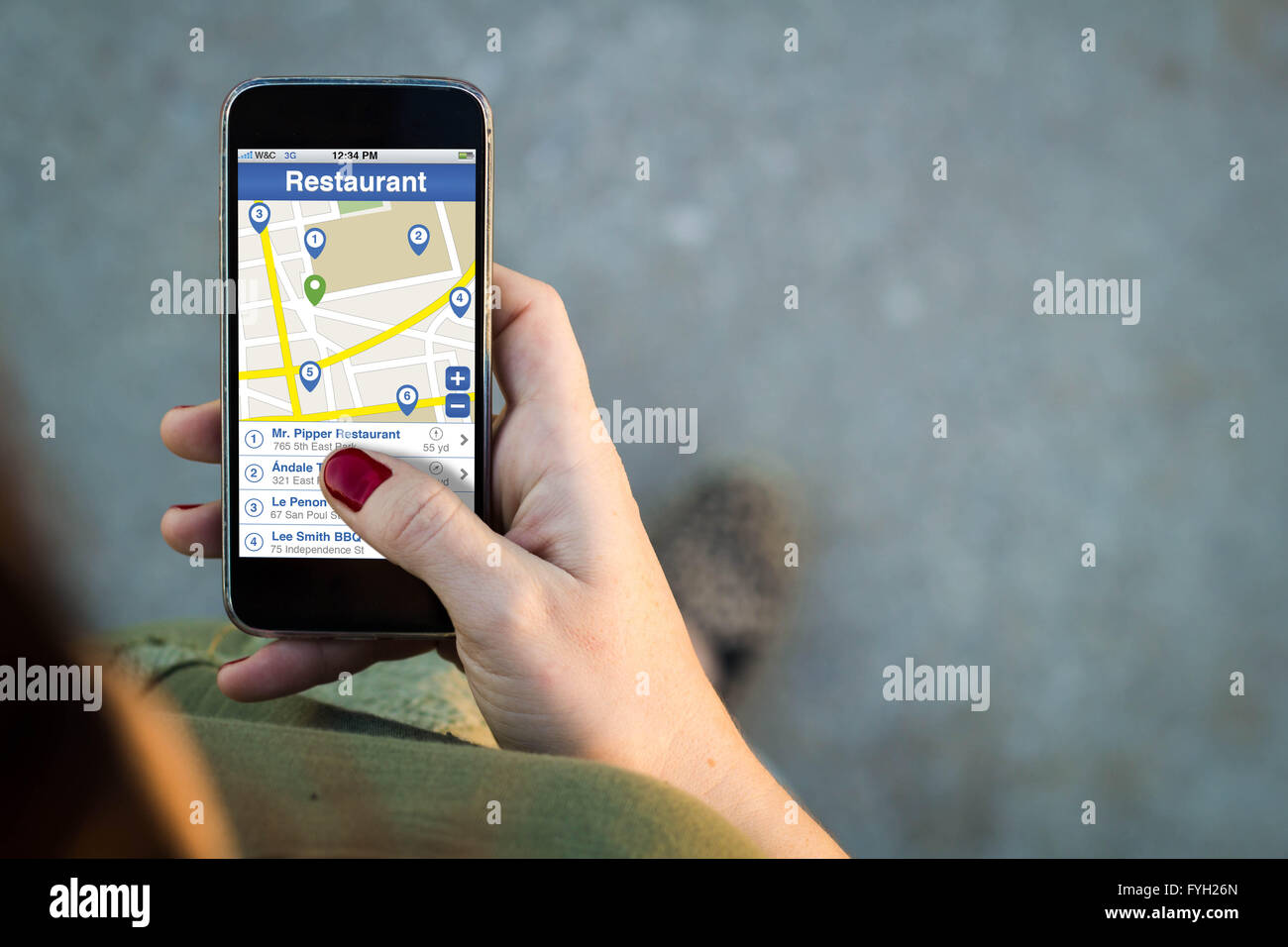 Vista superiore della donna a piedi in strada utilizzando il suo telefono cellulare con ristorante finder su schermo con copyspace. Tutto schermo grafico Foto Stock