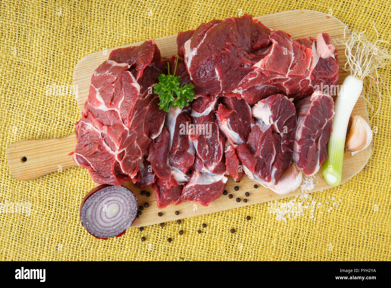 Carne di manzo crudo su tavola di legno con aglio e cipolle Foto Stock