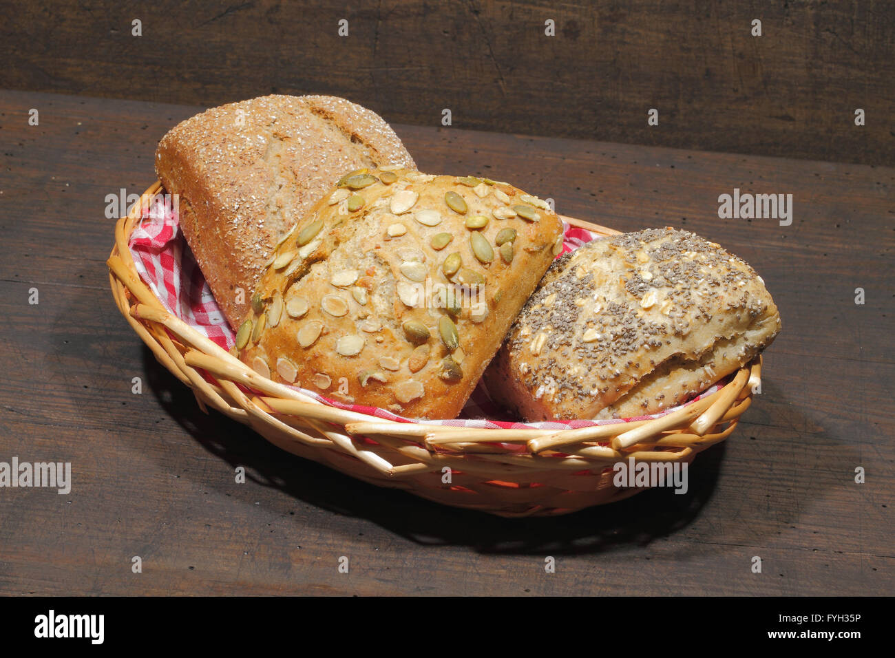 Vari tipi di pane, torte, bun, in un cestello, su un rustico, superficie in legno Foto Stock