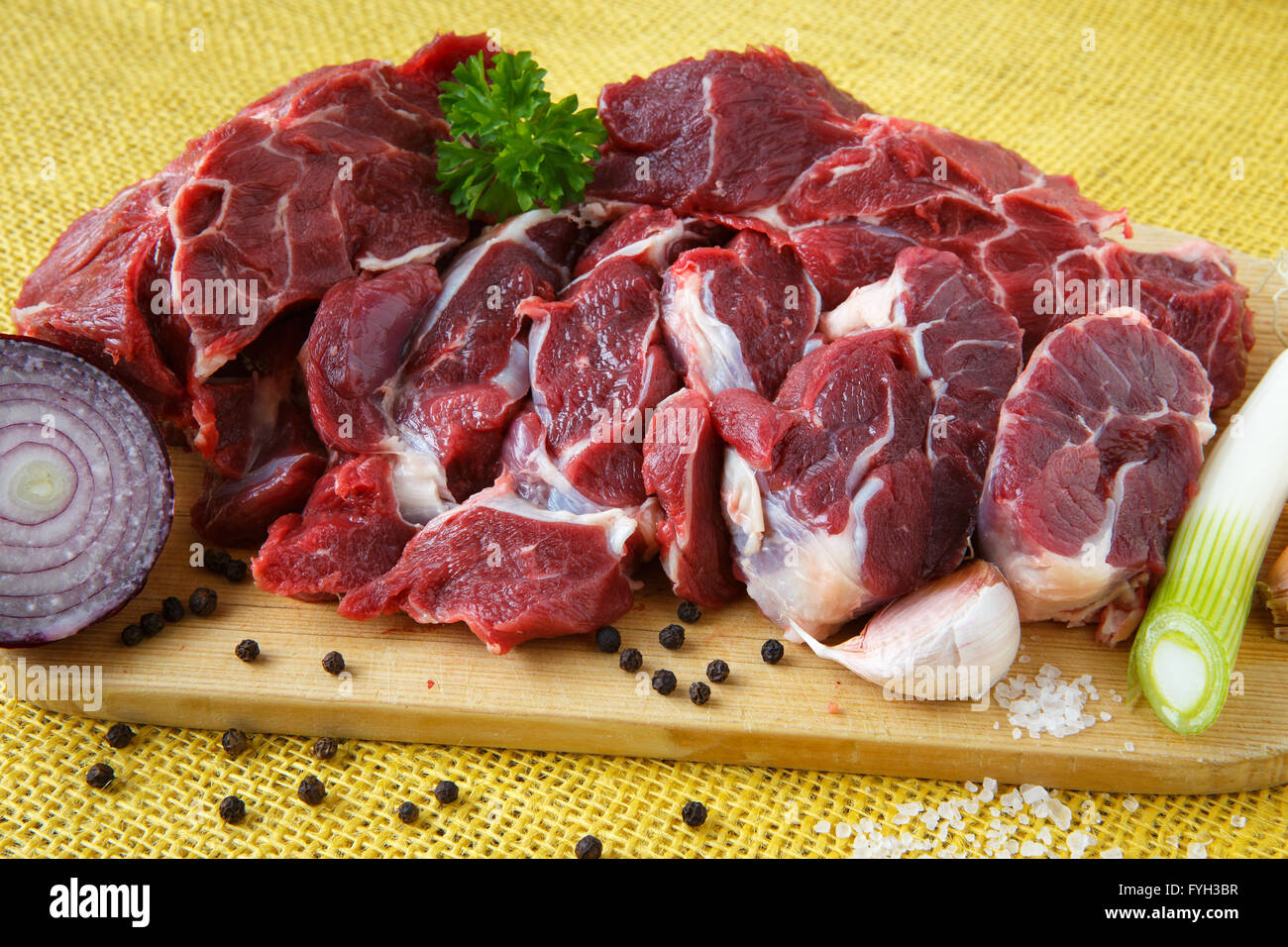 Carne di manzo crudo su tavola di legno con aglio e cipolle Foto Stock