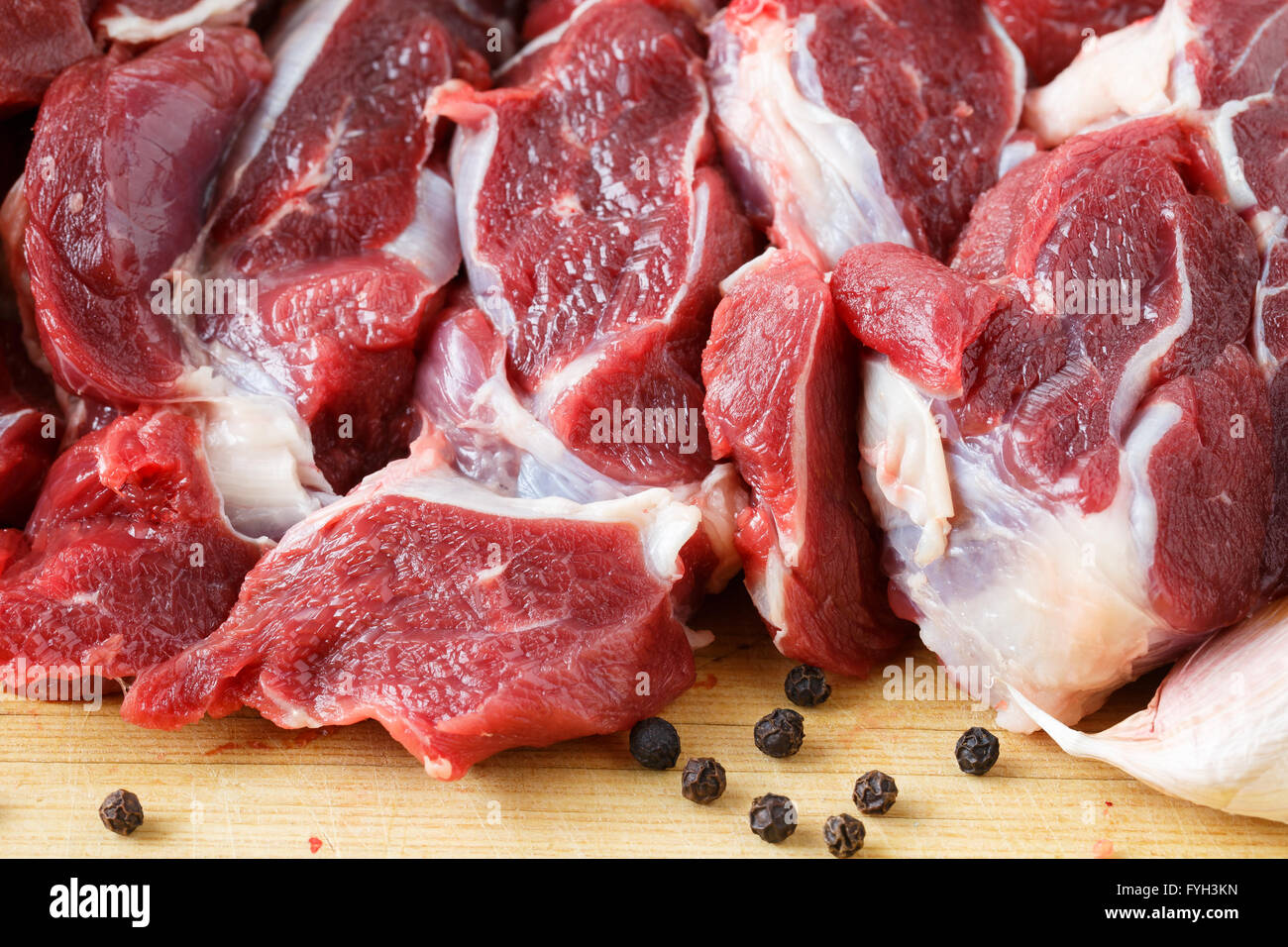 Pezzi di carne di manzo crudo su tavola di legno con spice Foto Stock