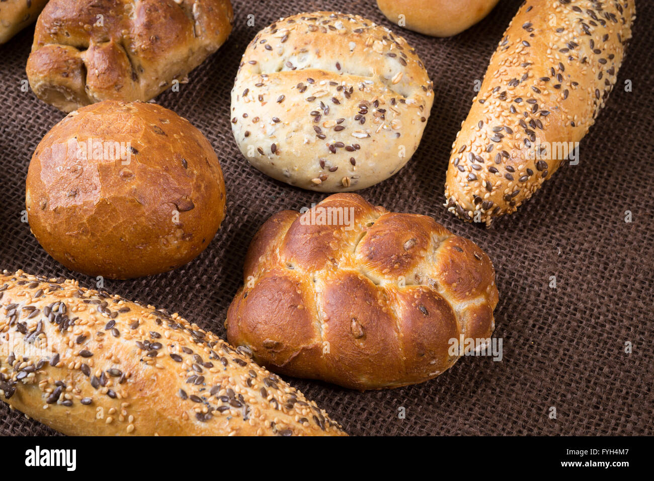 Diversi tipi di pane integrale e rotoli su sfondo marrone Foto Stock