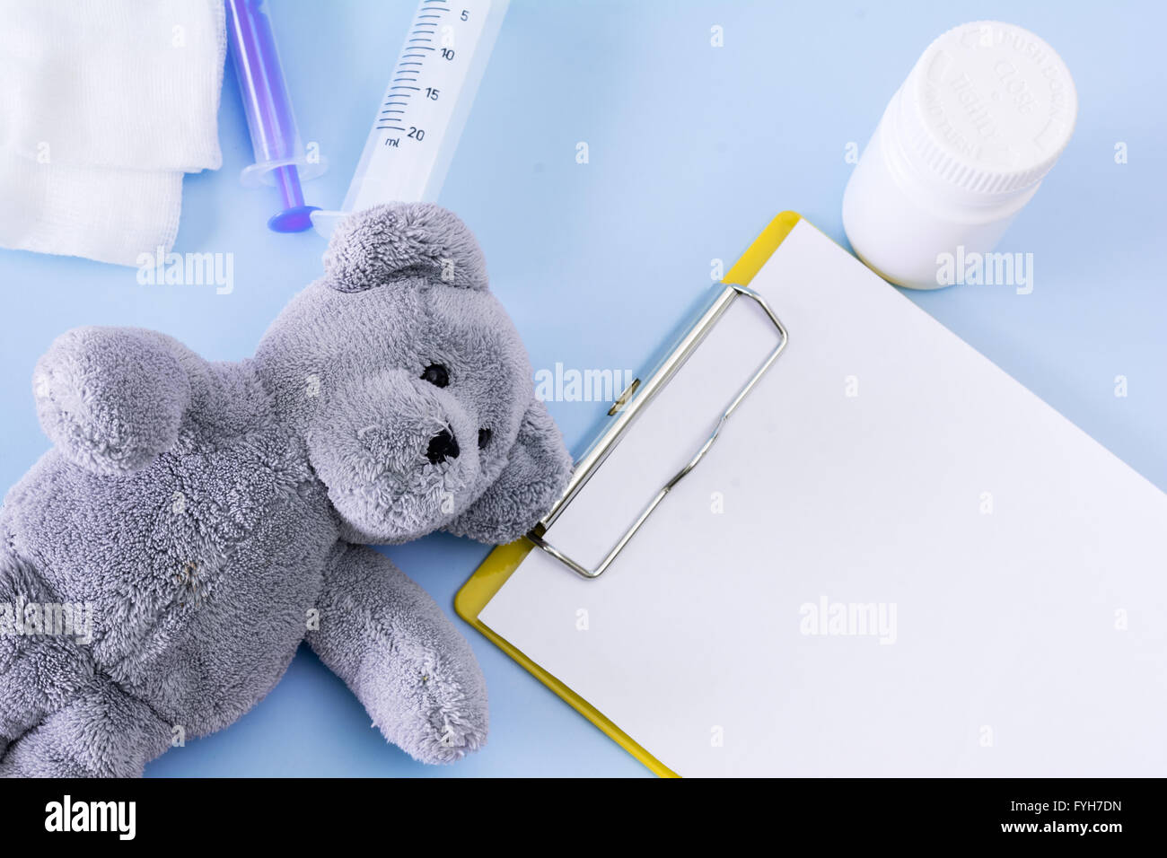 Medical quadro concettuale con le pillole, Teddy bear, iniezione, garza, bottiglia vuota del foglio di appunti. Foto Stock
