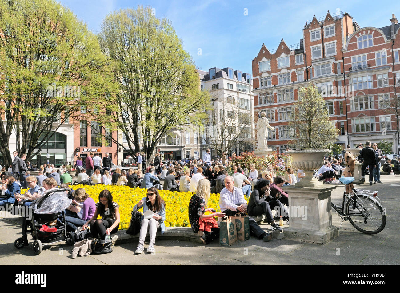 Persone rilassante in una giornata di sole in Golden Square, Soho, City of Westminster, Londra, Inghilterra, Regno Unito Foto Stock