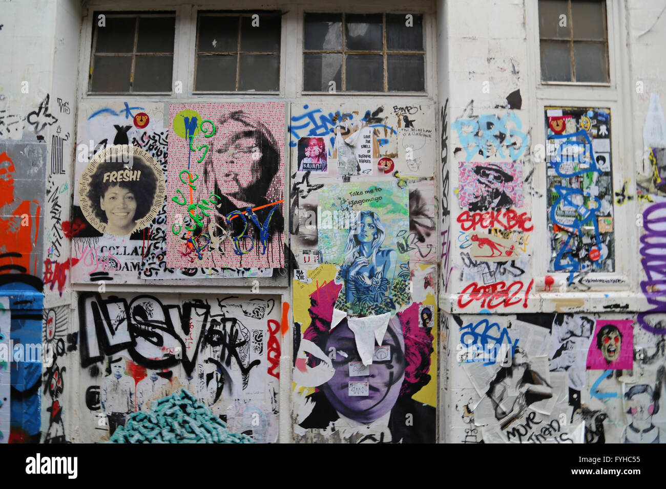 Graffiti e arte di strada nel quartiere alla moda di hipster area di Shoreditch a Londra, con poster e colori fino a parete. Foto Stock