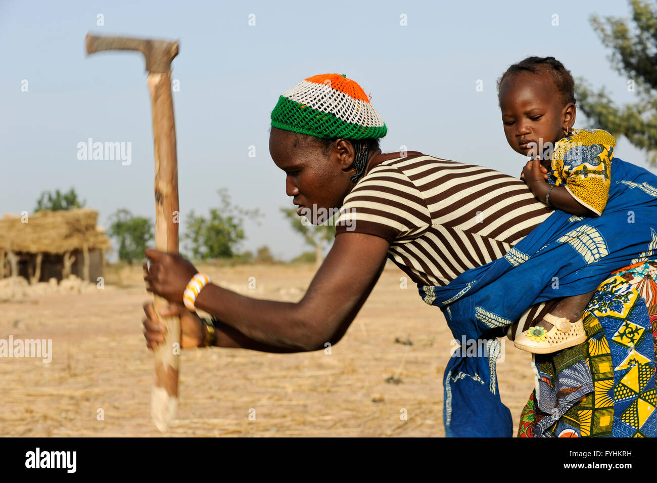 Il Burkina Faso, Bokin, Donna con bambino sulla schiena lavora con la zappa sul campo / BURKINA FASO, Bokin, Frau mit tipo auf dem Ruecken arbeite mit Hacke auf dem Feld Foto Stock