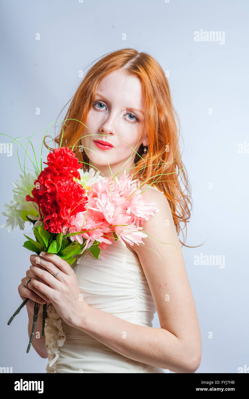 Redhead con mazzo di fiori in studio su bianco Foto Stock