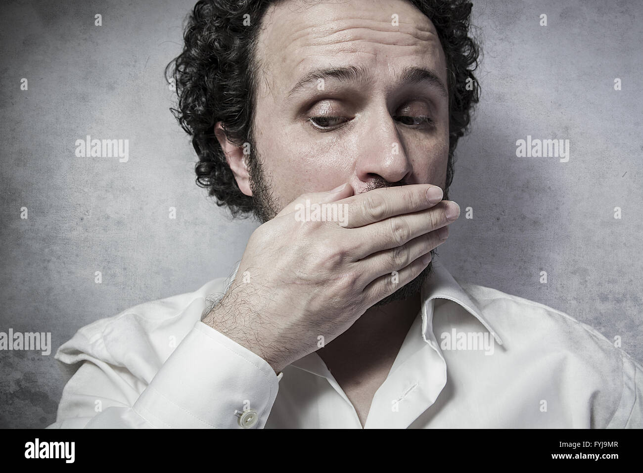 Imprenditore che copre la sua emouth, Uomo in camicia bianca con espressioni buffe Foto Stock