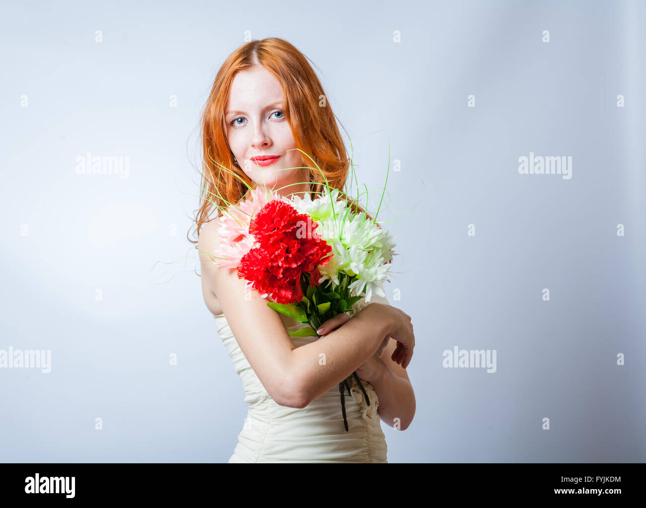 Redhead con mazzo di fiori in studio su bianco Foto Stock