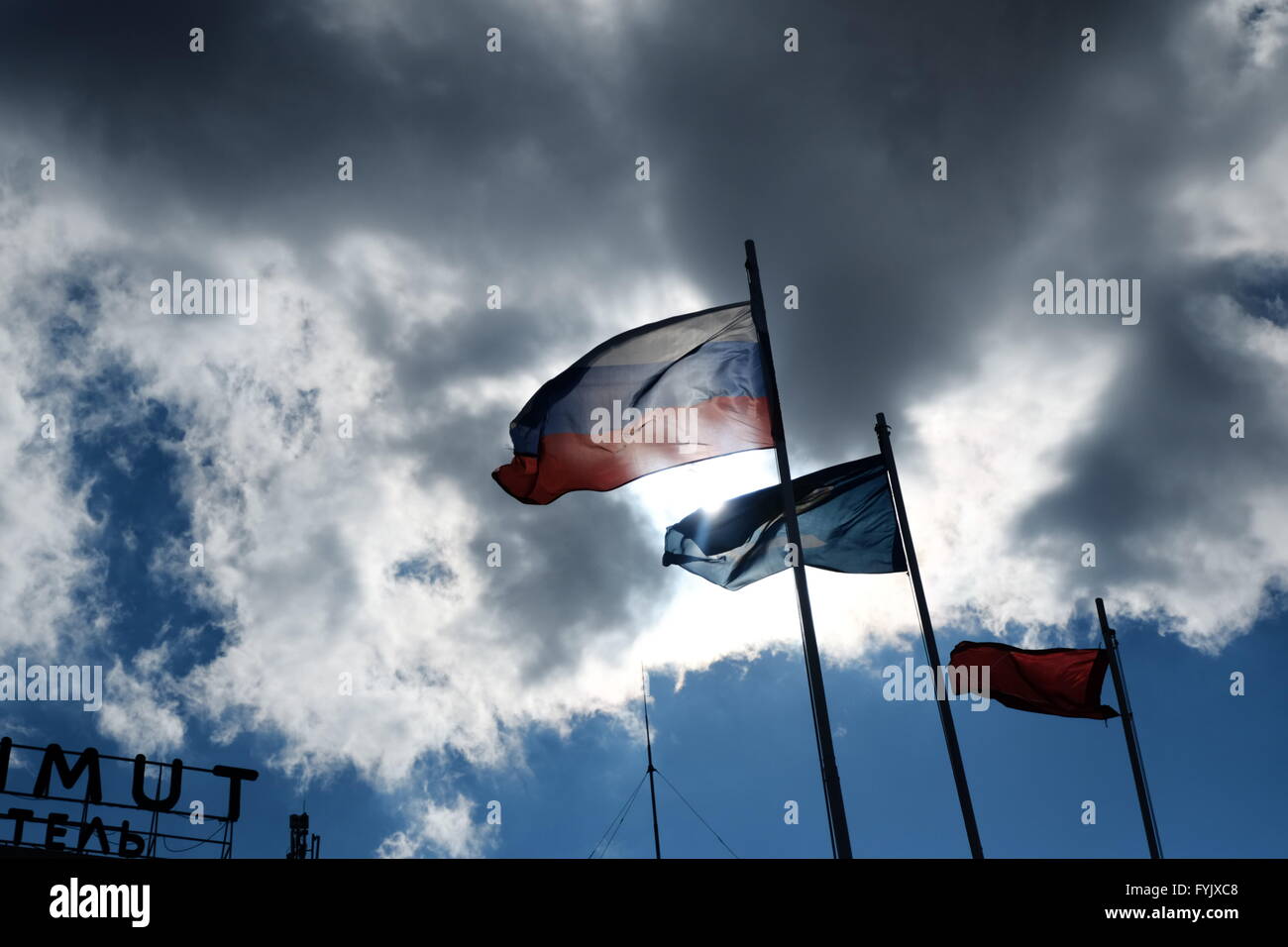 Bandiera russa sul vento contro damatic nuvole e la bandiera della regione di Astrakhan accanto Foto Stock