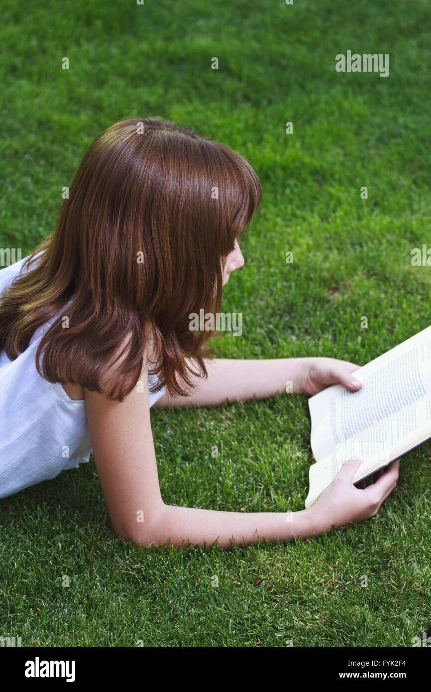 Uno.giovane bella ragazza la lettura di un libro per esterno Foto Stock