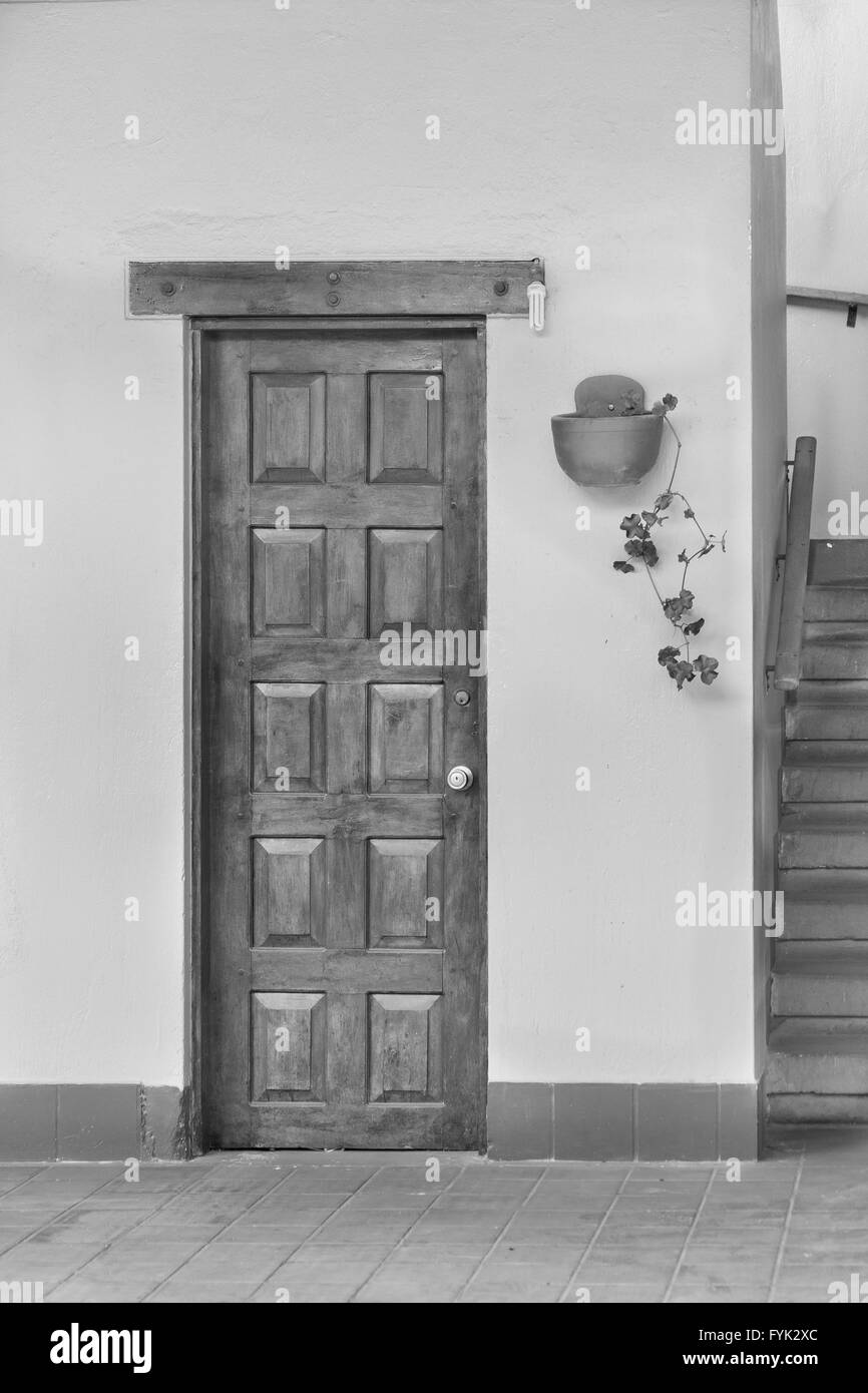 Foto in bianco e nero di vecchio stile porta di legno di una casa con un impianto e una scalinata accanto. Foto Stock