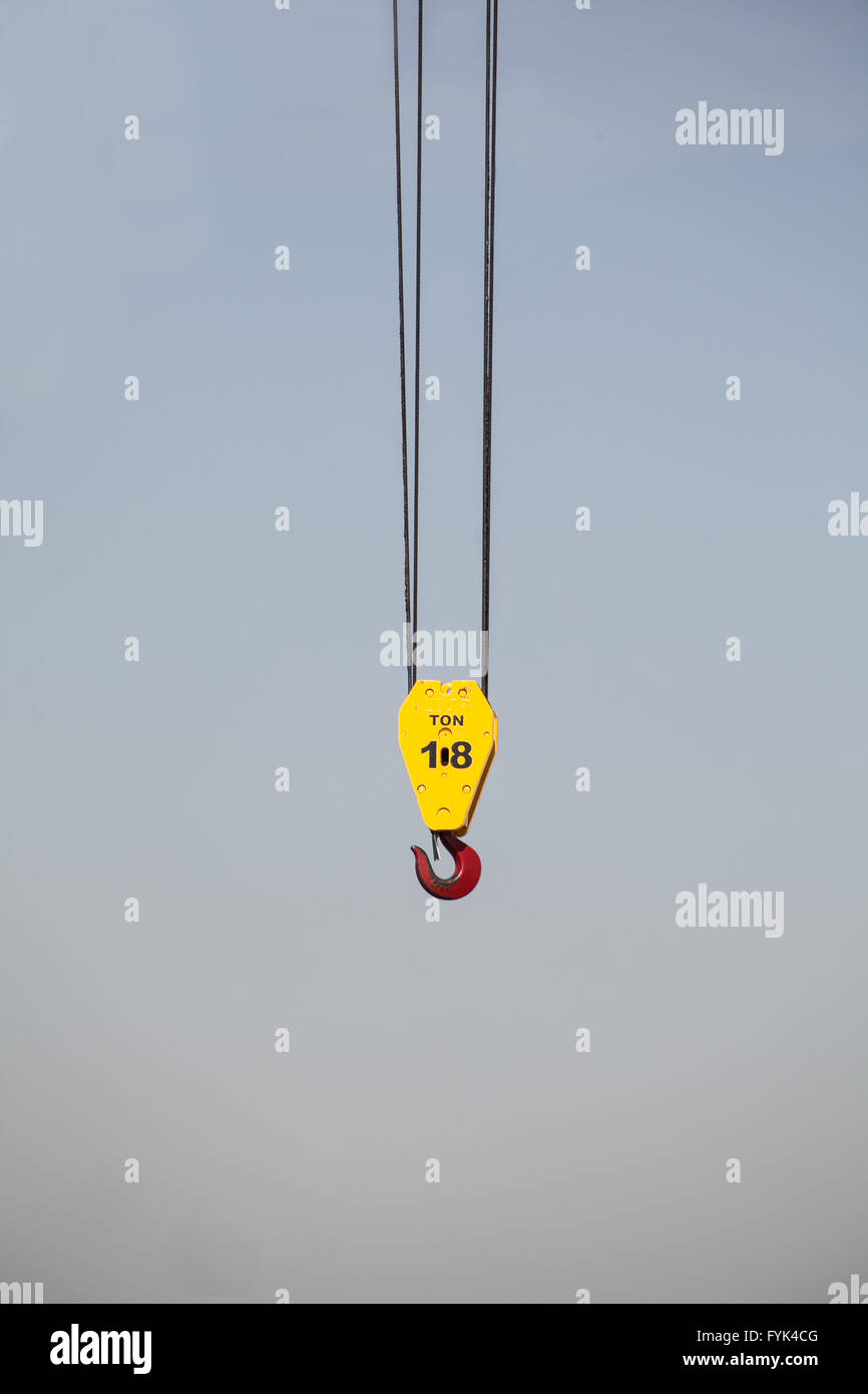 Un gancio forte e la puleggia appeso con 2 cavi w una pinza red hook per trasportare pesanti le cose. È appesa a una gru in cielo. Foto Stock