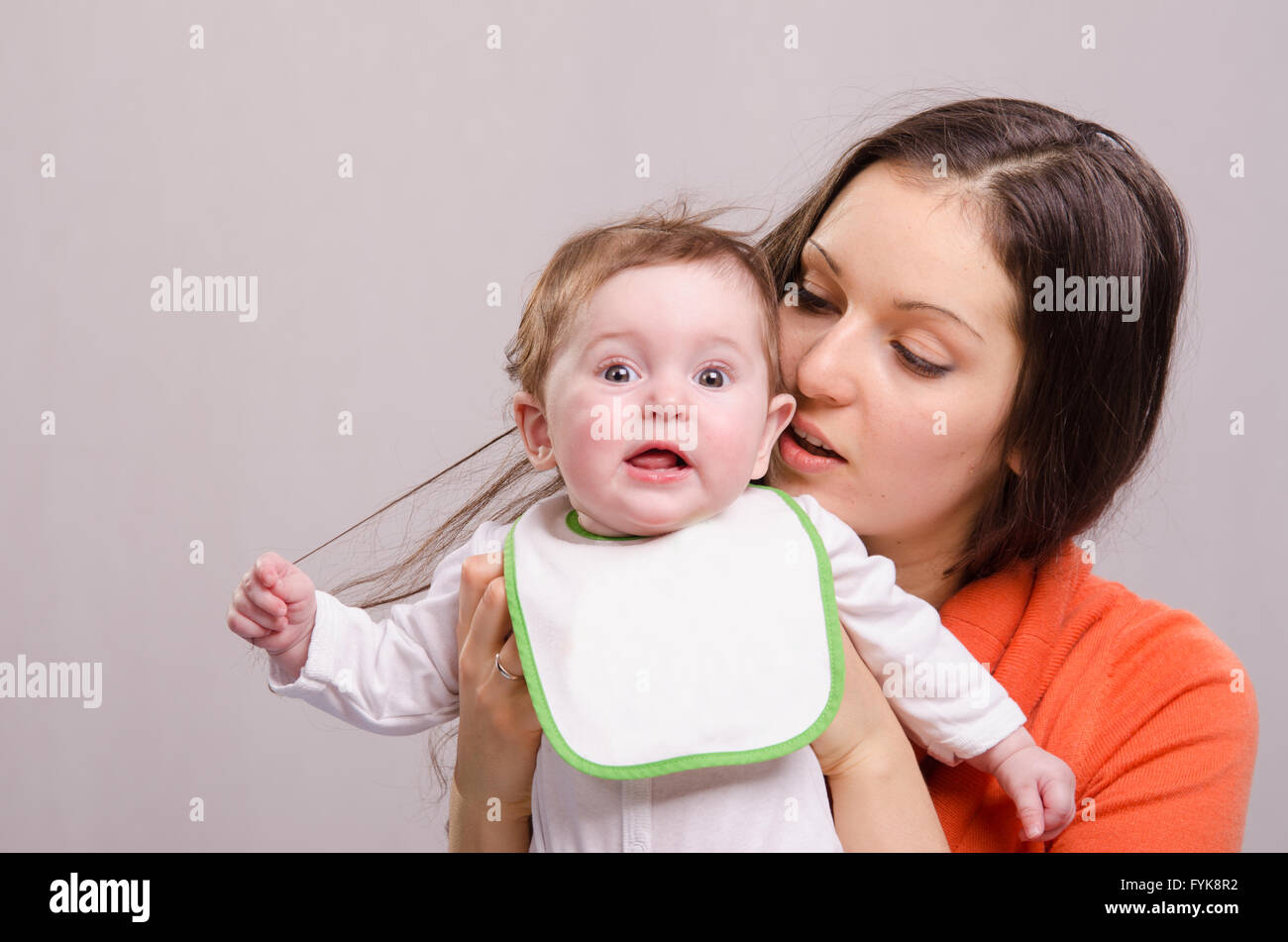 Sei mesi di bambina in bib strappare i capelli mom Foto Stock