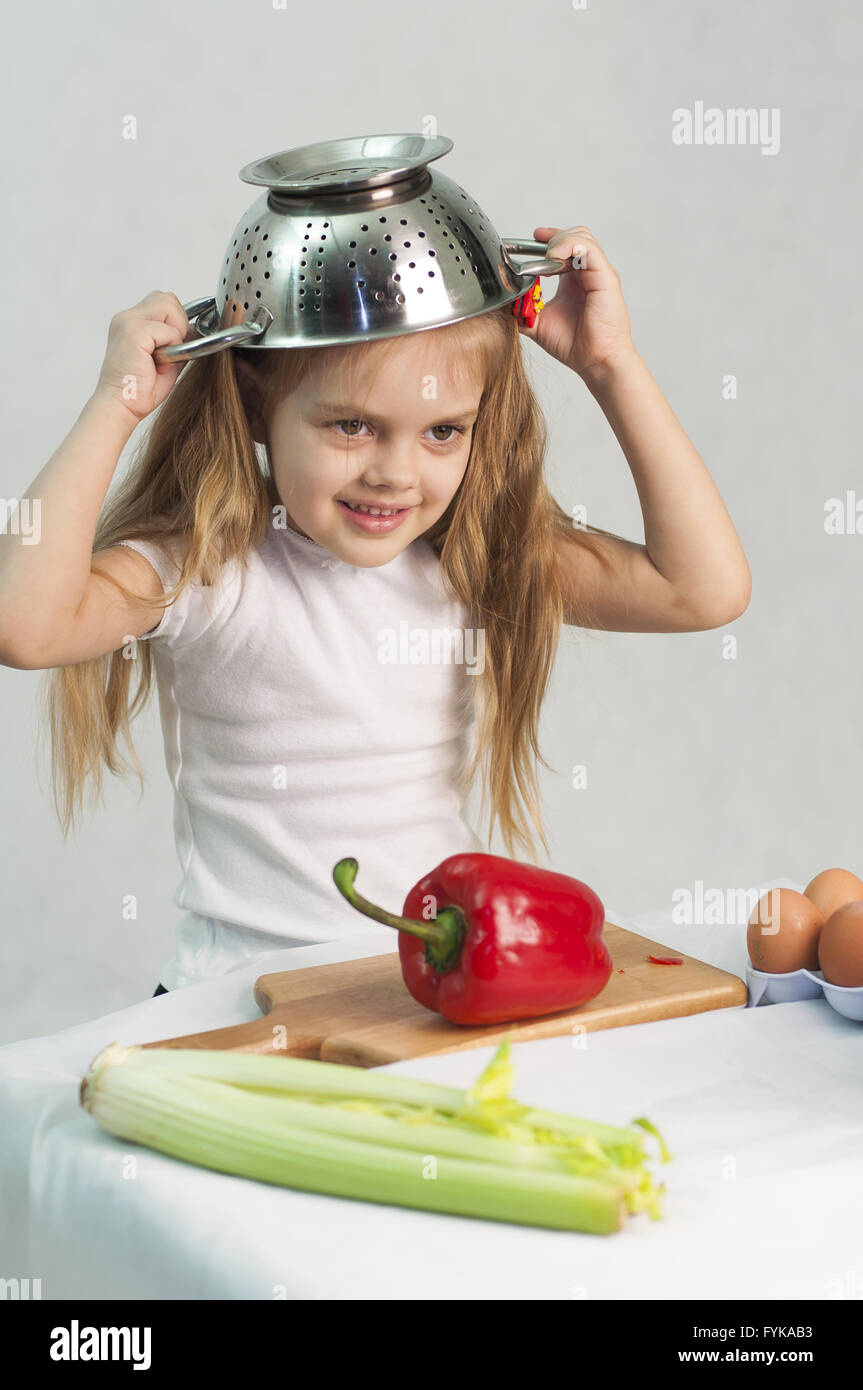 Ragazza che gioca in cook mettere un colapasta sulla sua testa Foto Stock