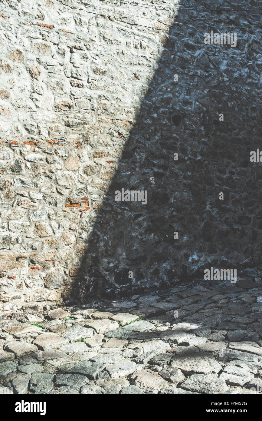 Mattone antico muro di pietra e strada asfaltata Foto Stock