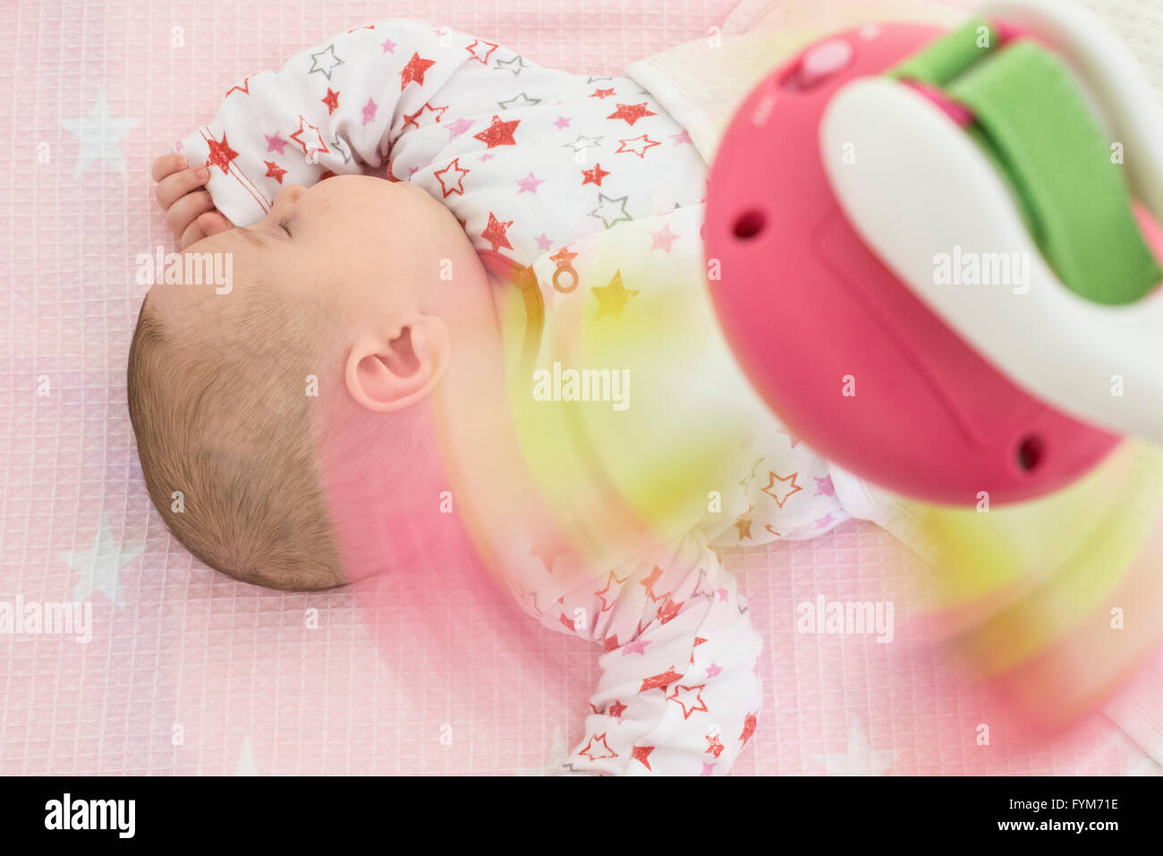 Baby girl in un letto con i giocattoli intorno a. I toni di colore rosa Foto Stock