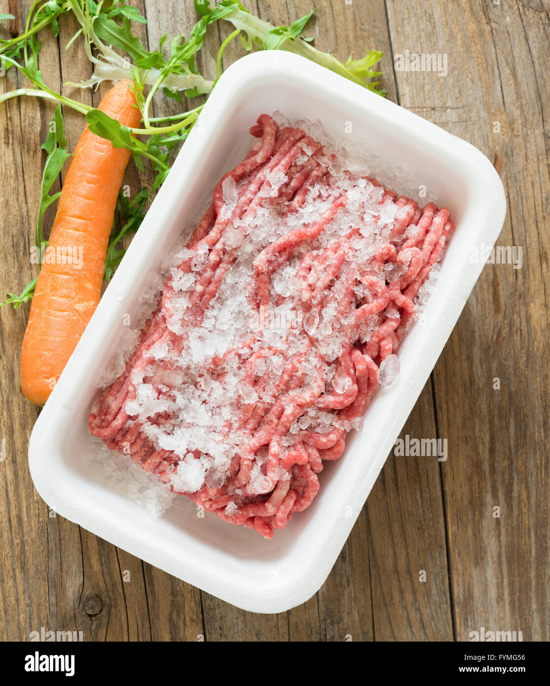 Massa congelata la carne bovina in contenitore di polistirolo su legno Foto Stock