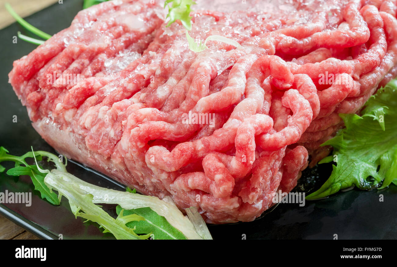 Massa congelata la carne bovina in contenitore di polistirolo su legno Foto Stock