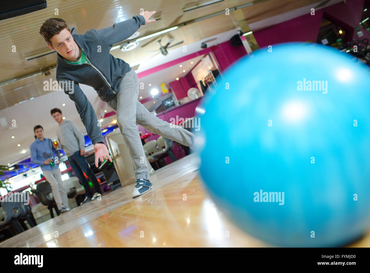 Giovane uomo gettando palla da bowling Foto Stock