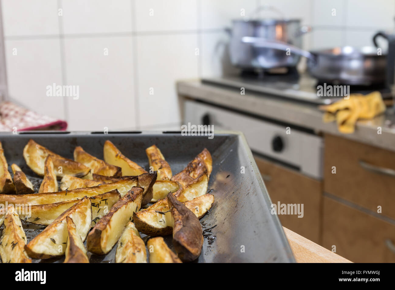 Vassoio di Spicchi di patate contro lo sfondo di cucina Foto Stock
