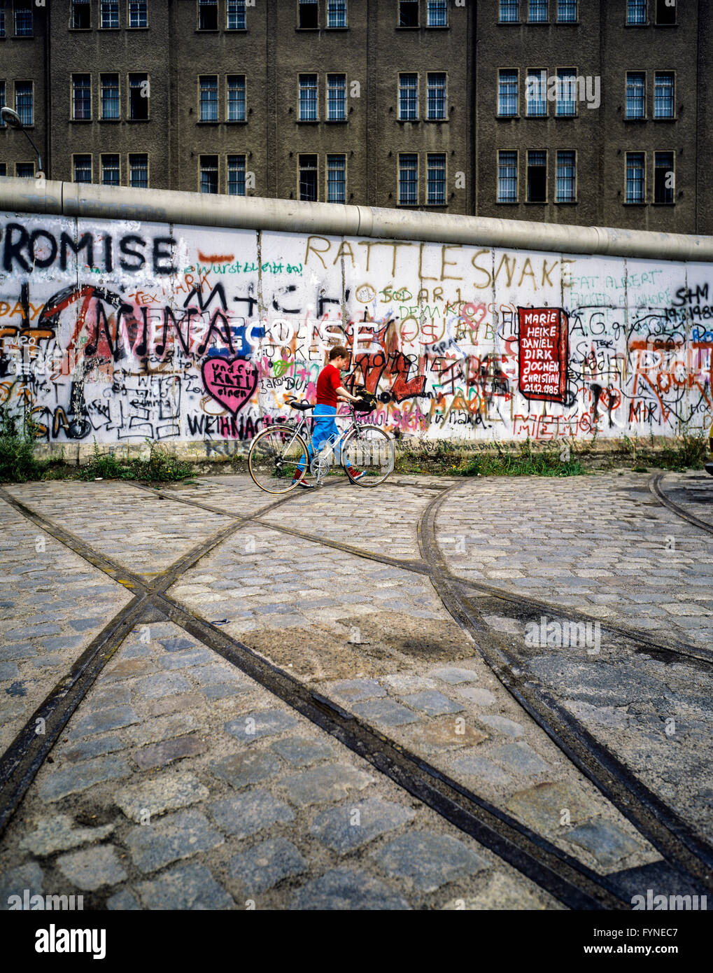 Agosto 1986, muro di Berlino graffitis, tram via terminante in parete, ciclista, Berlino Est edificio, Berlino Ovest lato, Germania, Europa Foto Stock