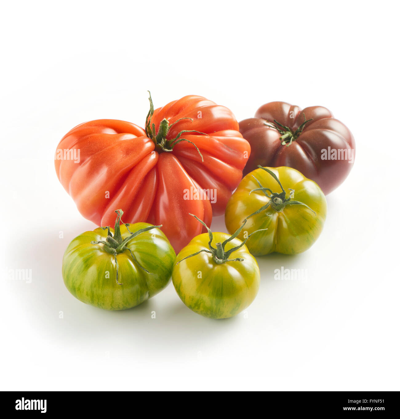 Un assortimento di cultivar di pomodoro fresco verde con tiger, coeur de boeuf e pomodori nero su sfondo bianco con copyspace Foto Stock