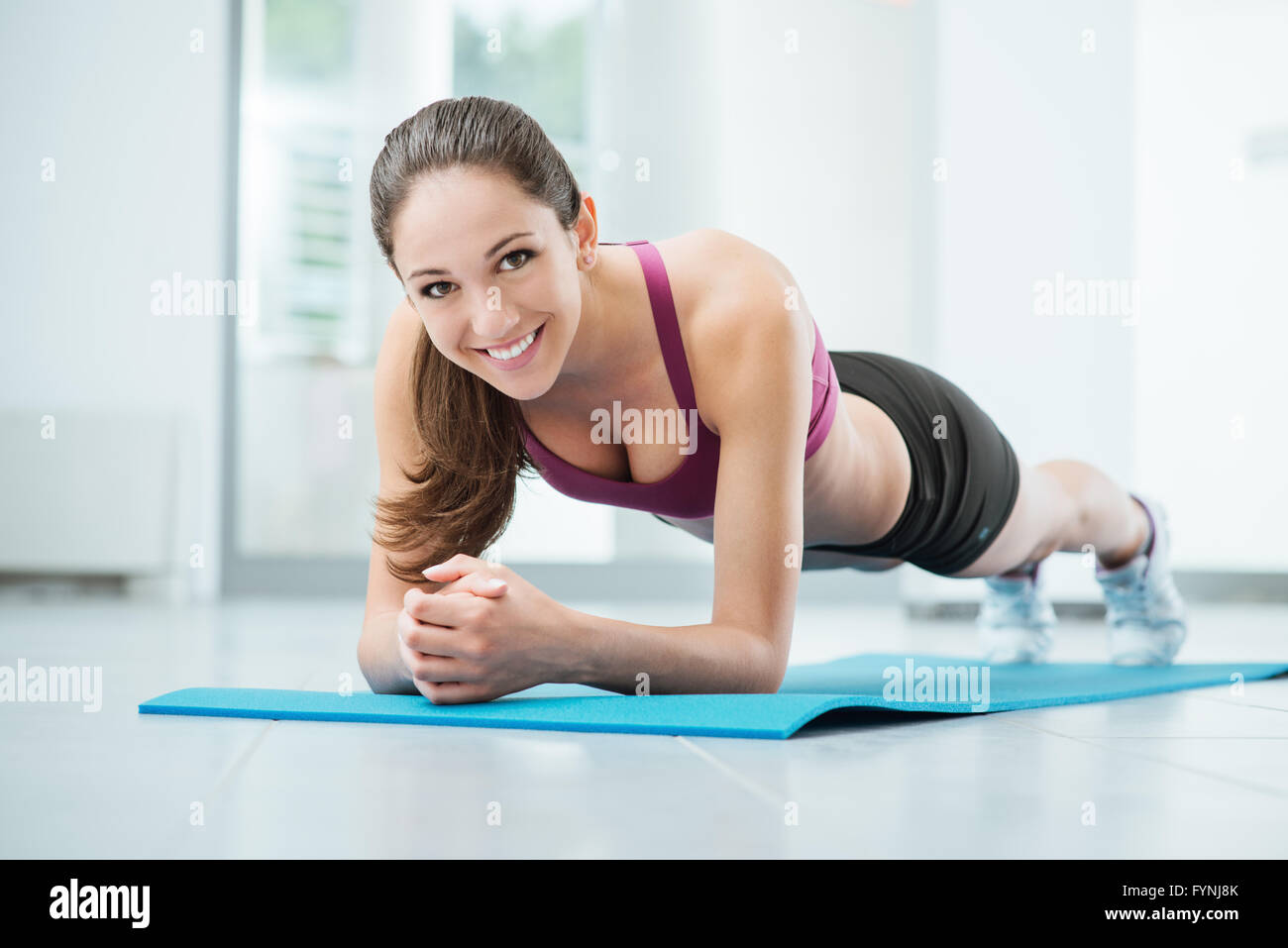Donna sorridente esercizi in palestra su un tappetino, fitness e concetto di allenamento Foto Stock