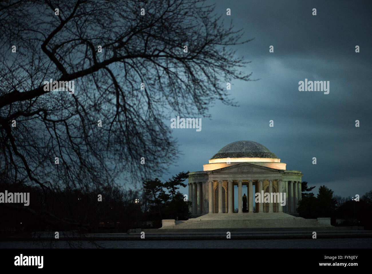 WASHINGTON DC - Un ciliegio nudo si staglia contro il cielo lungo il bacino delle maree, con il Jefferson Memorial visto in lontananza. I famosi ciliegi Yoshino della zona, un regalo del Giappone nel 1912, attirano visitatori ogni primavera per il National Cherry Blossom Festival. Il memoriale neoclassico è dedicato a Thomas Jefferson, il terzo presidente degli Stati Uniti. Foto Stock