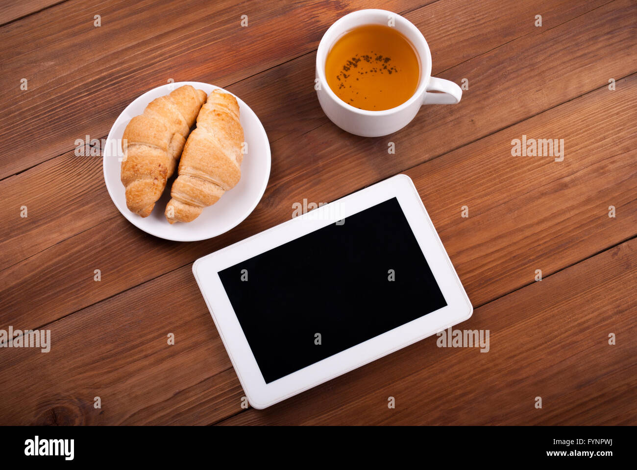 Tazza di tè tablet croissant su una tavola di legno. Foto Stock