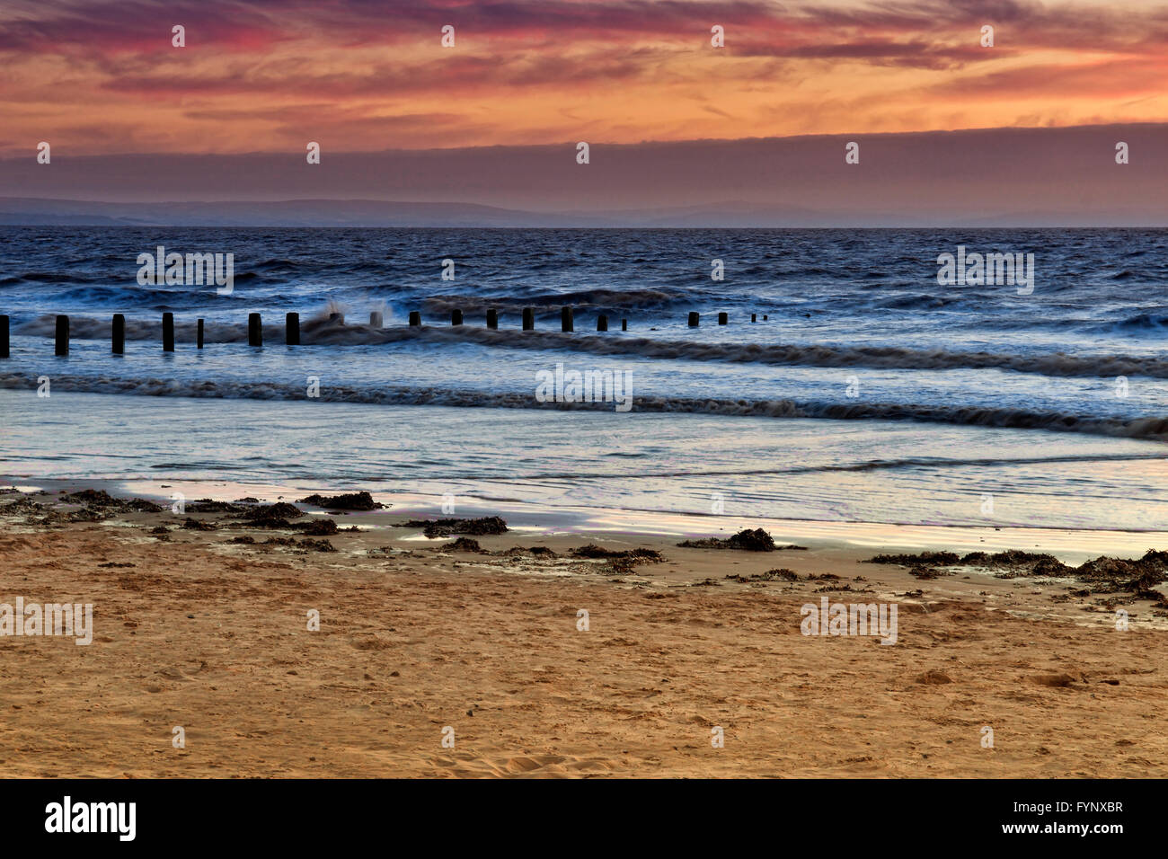 Tramonto a Berrow Beach, Burnham-On-Mare, Somerset, Regno Unito con pennelli andando per mare Foto Stock