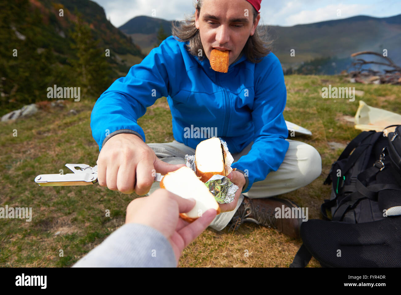 Escursionismo uomo slice gustoso formaggio su picnic Foto Stock