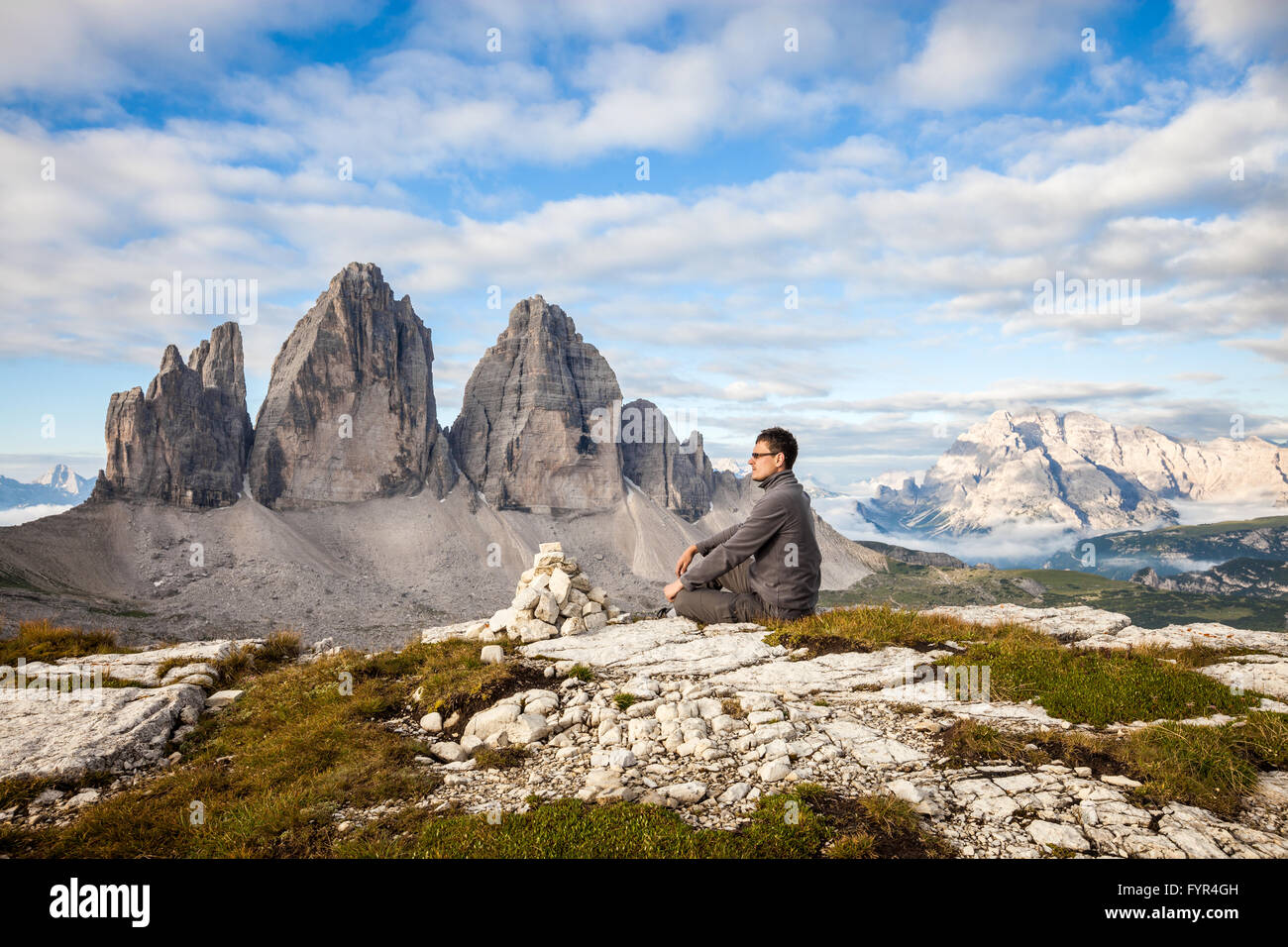 Uomo seduto sulla cima della montagna Foto Stock