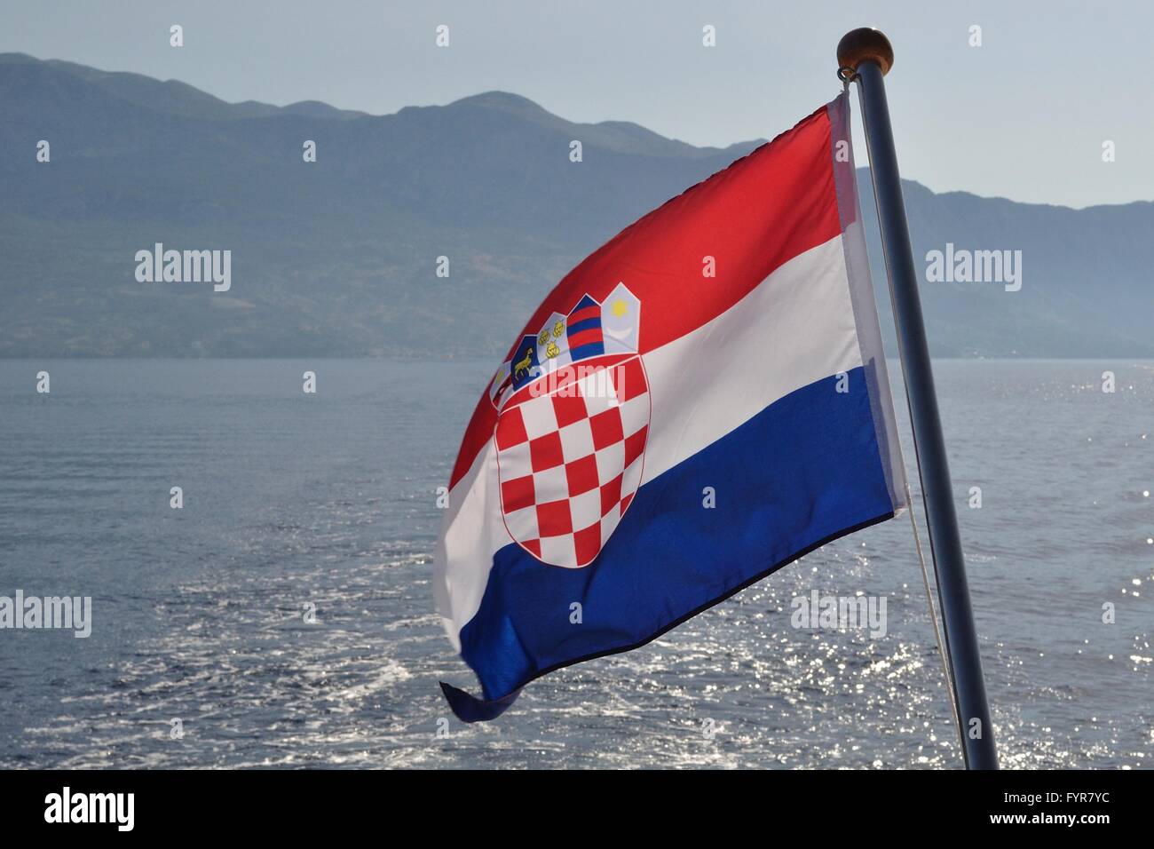 Nazionale croata battenti bandiera a giornata di vento con mare adriatico in background Foto Stock