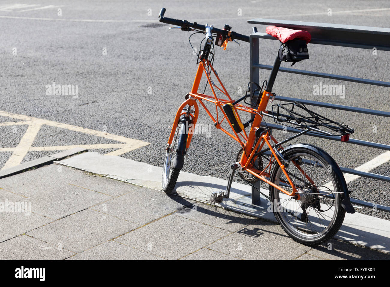 Un arancione Moulton space frame piccola ruota bike bloccato da una recinzione in Newcastle upon Tyne, Tyne and Wear, England, Regno Unito Foto Stock