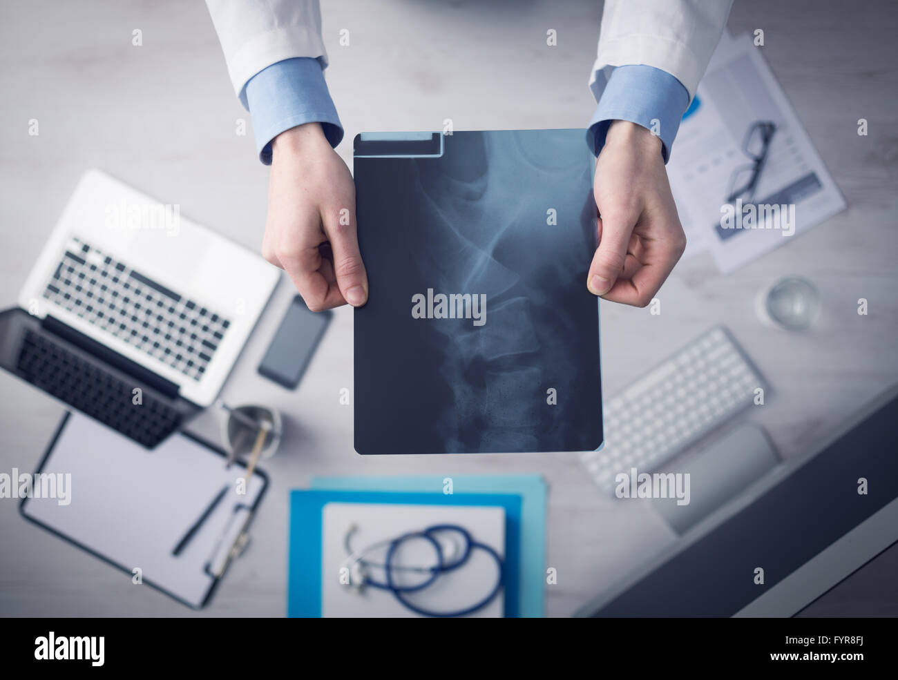 Radiologo cheching un'immagine a raggi x della colonna vertebrale umana, mani close up con desktop sullo sfondo, vista dall'alto Foto Stock