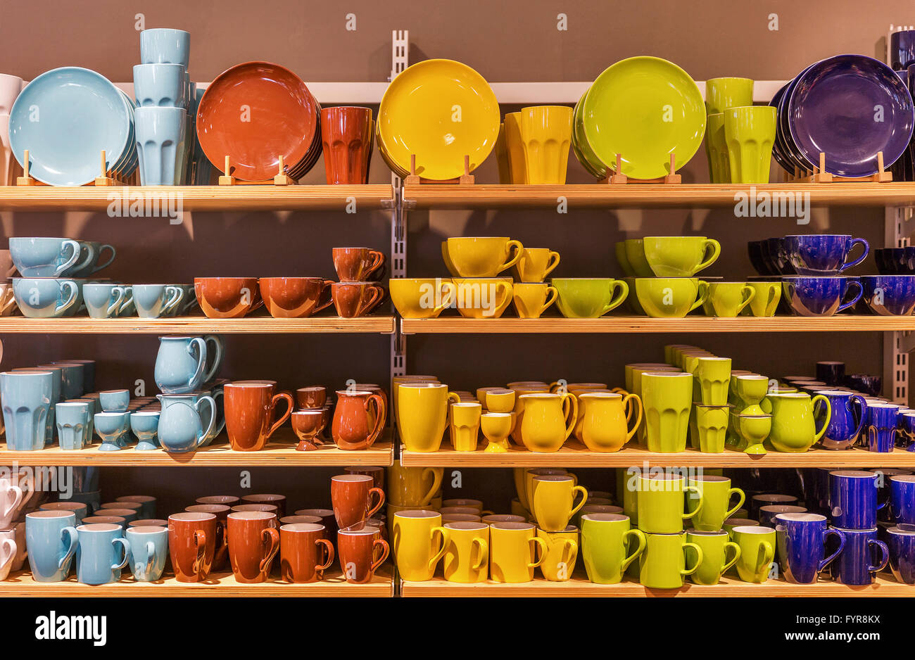 Display di vendita al dettaglio di variopinti piatti di porcellana e tazze sui ripiani. Foto Stock