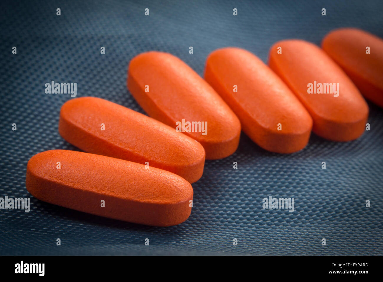 Macro close up orange killer del dolore pillole su sfondo blu Foto Stock