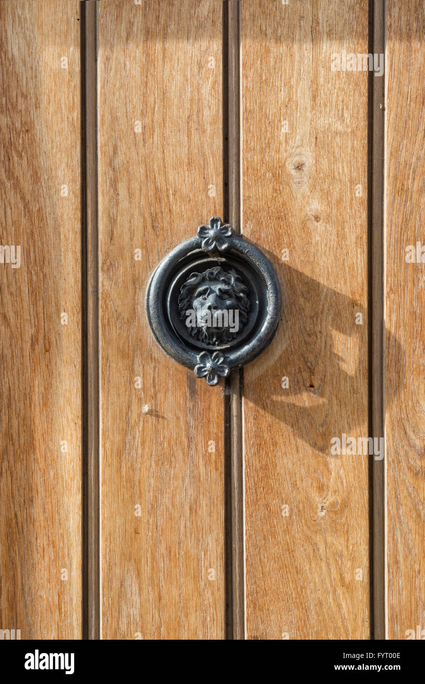 Testa leone porta respingente su una tavola di legno porta anteriore. Cotswolds, REGNO UNITO Foto Stock