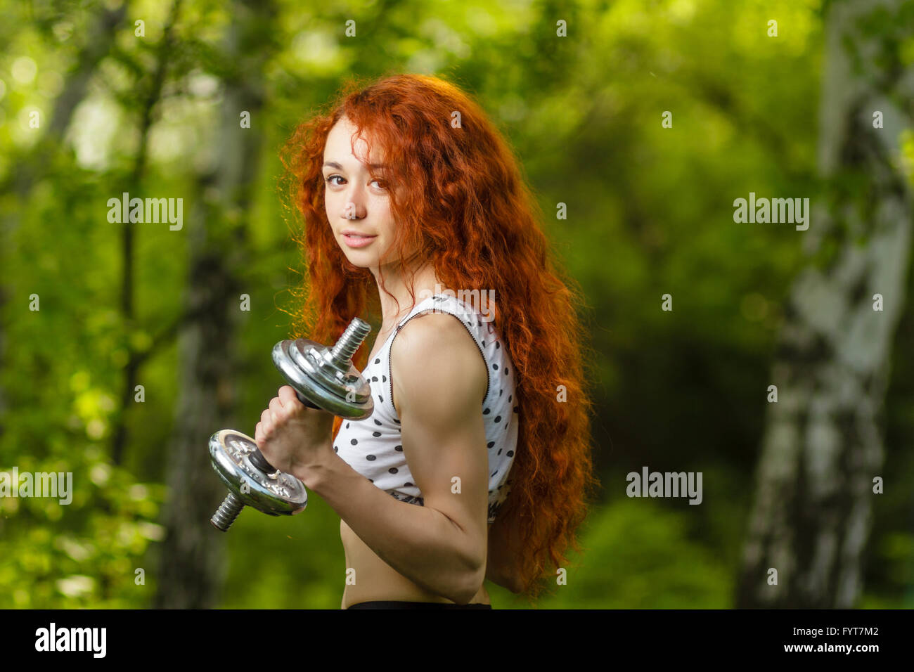Redhead girl esercizio con manubri in foresta Foto Stock