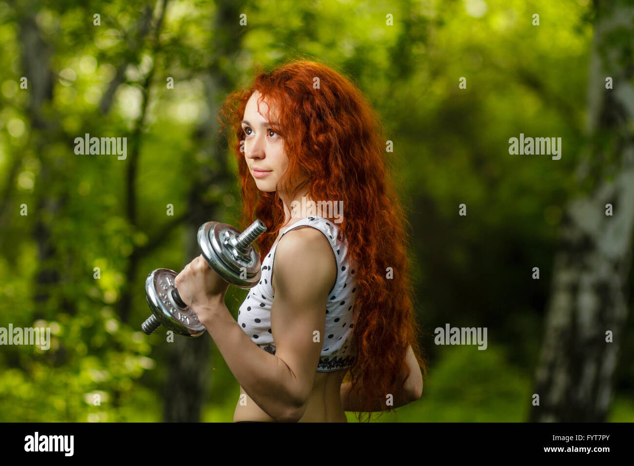 Redhead girl esercizio con manubri in foresta Foto Stock